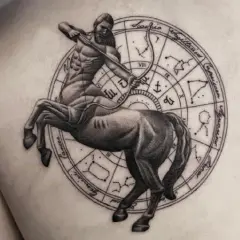 Tatuaż strzelec: centaur z łukiem i strzałą na tle koła zodiaku.