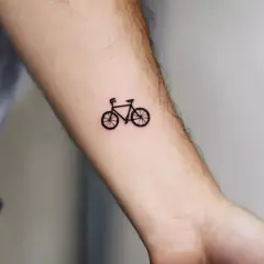 Minimalistyczny tatuaż rower szosowy na przedramieniu. Symbol wolności i pasji do podróży.