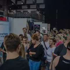 Ludzie na konwencie tatuażu, gdzie widoczny jest symbol autyzmu na banerze "Przystań Autys".