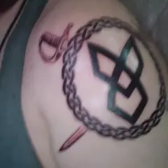 Tatuaż wojownik na ramieniu: spleciony łańcuch, szabla i symbol.