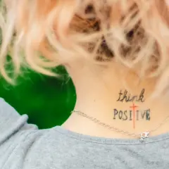 Mądre cytaty na tatuaż: "think POSITIVE" wytatuowane na karku, przypomina o pozytywnym nastawieniu.
