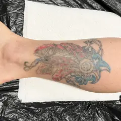 Kolorowy tatuaż w stylu irezumi polska na łydce, przedstawiający stylizowanego ptaka lub smoka.