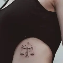 Delikatny tatuaż waga znak zodiaku na boku, ozdobiony gwiazdami.