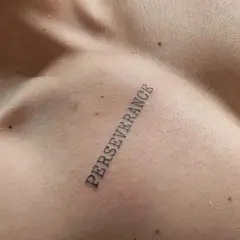 Tatuaż na klatce piersiowej z napisem "PERSEVERANCE" symbolizujący siłę i wytrwałość w dążeniu do celu.