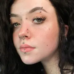 Dziewczyna z wieloma kolczykami, w tym kolczyk w brwi, septum i na ustach.