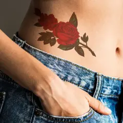 Piękny tatuaż róża na brzuchu, ozdobiony zielonymi liśćmi, dodaje uroku.