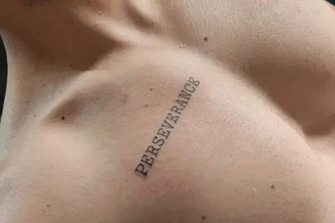 Tatuaż na klatce piersiowej z napisem "PERSEVERANCE" symbolizujący siłę i wytrwałość w dążeniu do celu.