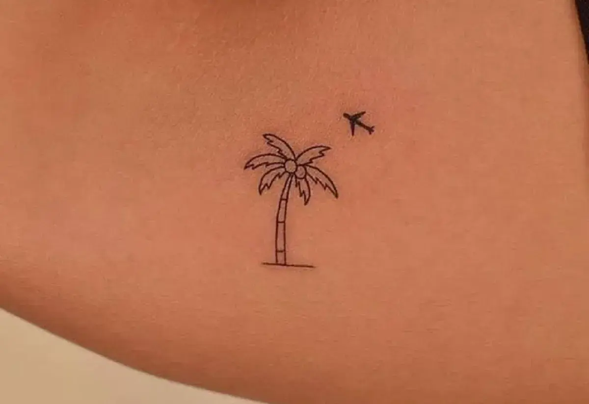 Minimalistyczny tatuaż palma z kokosami i lecącym samolotem. Symbol podróży i wakacji.