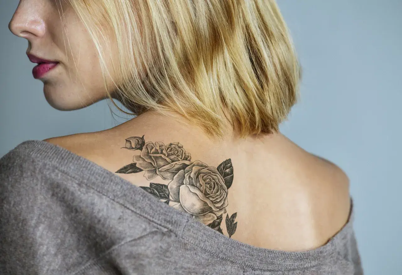 Mroczne tatuaże w kształcie róż zdobią plecy kobiety.