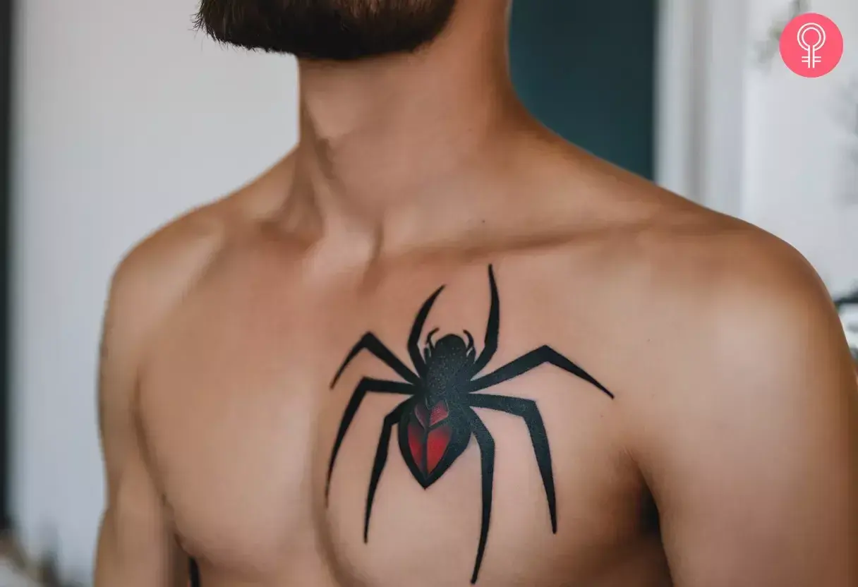 Mocny spiderman tatuaz na klatce piersiowej. Czarny pająk z czerwonym odwłokiem, symbolizujący siłę i determinację.
