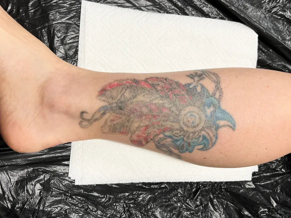 Kolorowy tatuaż w stylu irezumi polska na łydce, przedstawiający stylizowanego ptaka lub smoka.
