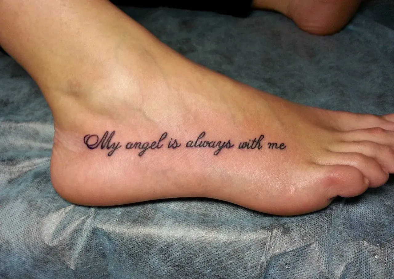 Najciekawsze tatuaż na stopie: napis "My angel is always with me" w eleganckiej czcionce.