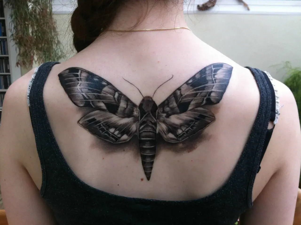 Realistyczny tatuaż ćmy na plecach. Symbolizuje transformację, intuicję i mądrość.