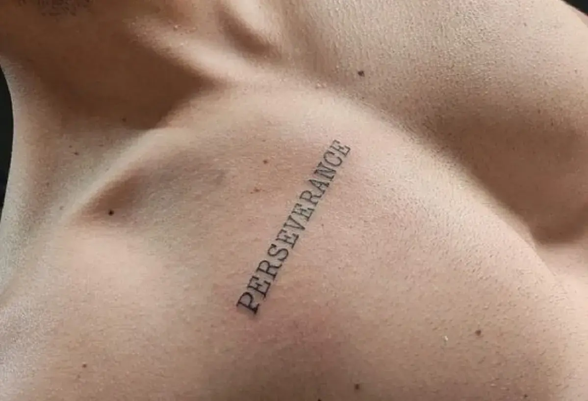 Tatuaż na klatce piersiowej z napisem "PERSEVERANCE" symbolizujący siłę i wytrwałość w dążeniu do celu.