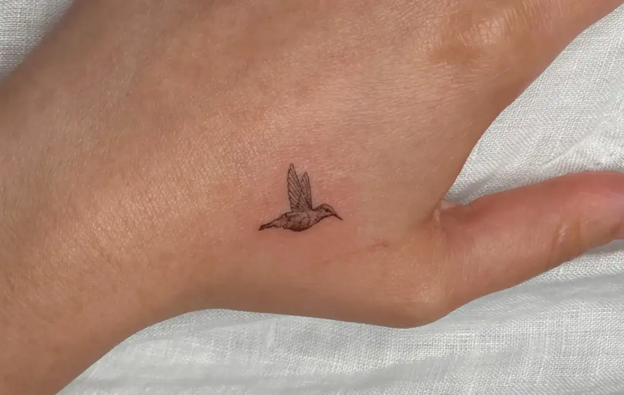 Delikatny koliber tattoo small na dłoni, symbol lekkości i wolności.